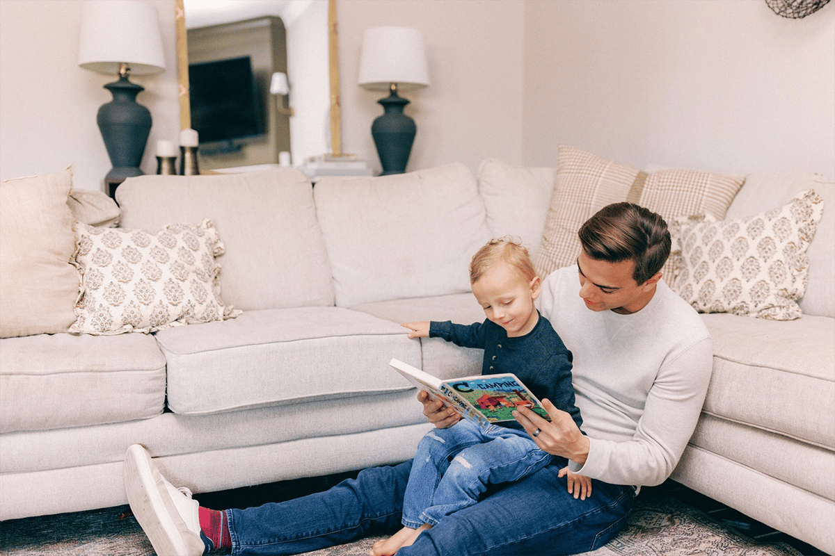 Young father reading to his soon in the living room