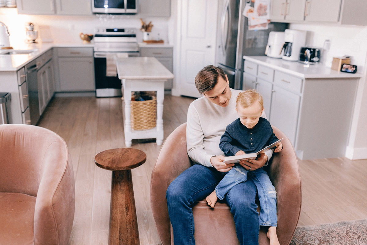 Parent reading to his son in a chair in the living room