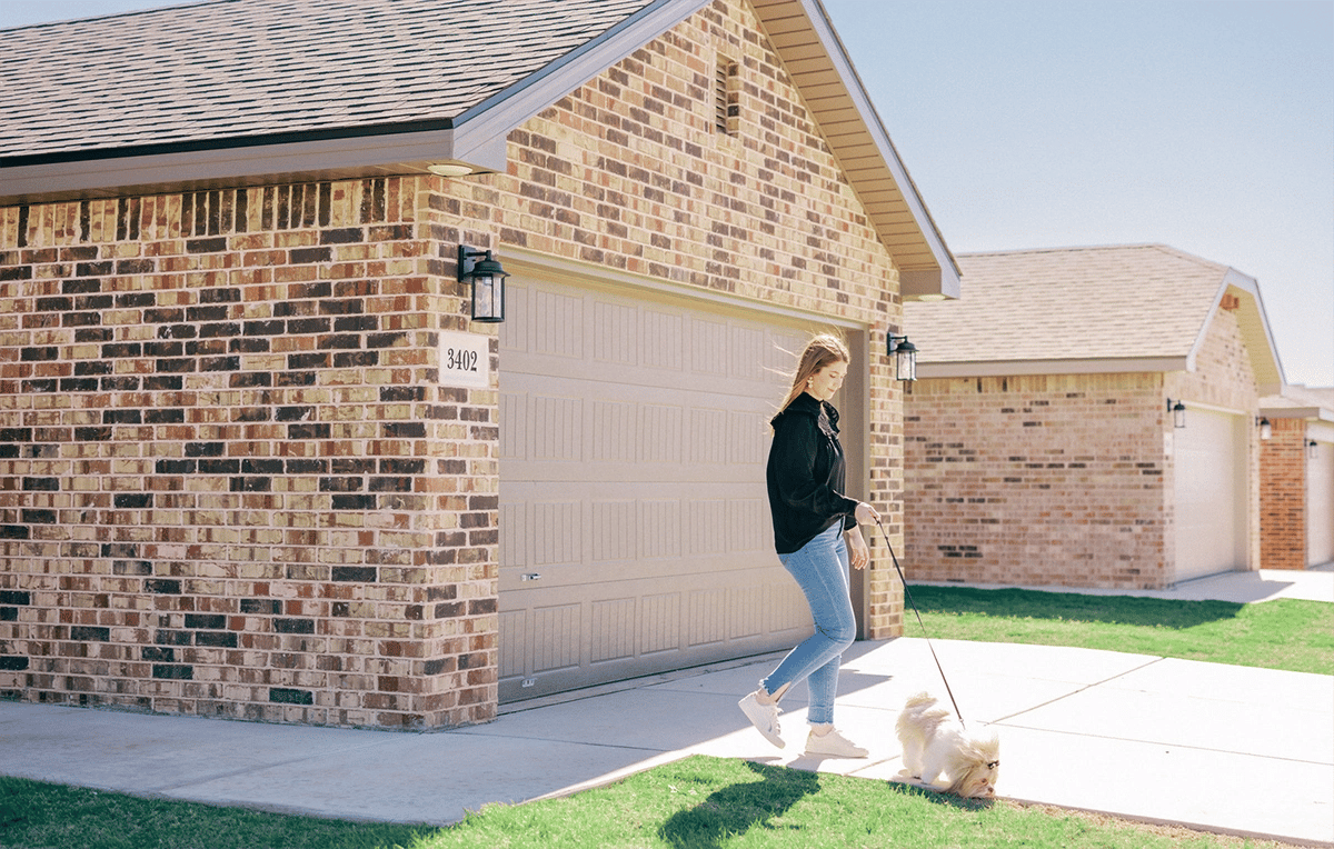 Young girl walking her dog in front of her home