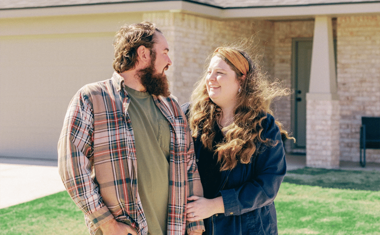 Young couple smiling together in front of their house