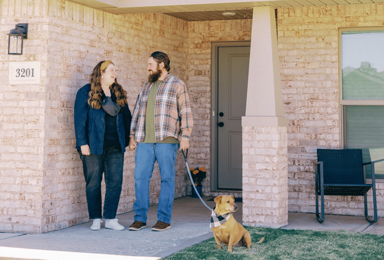 Couple with their dog standing in front of their new Betenbough home