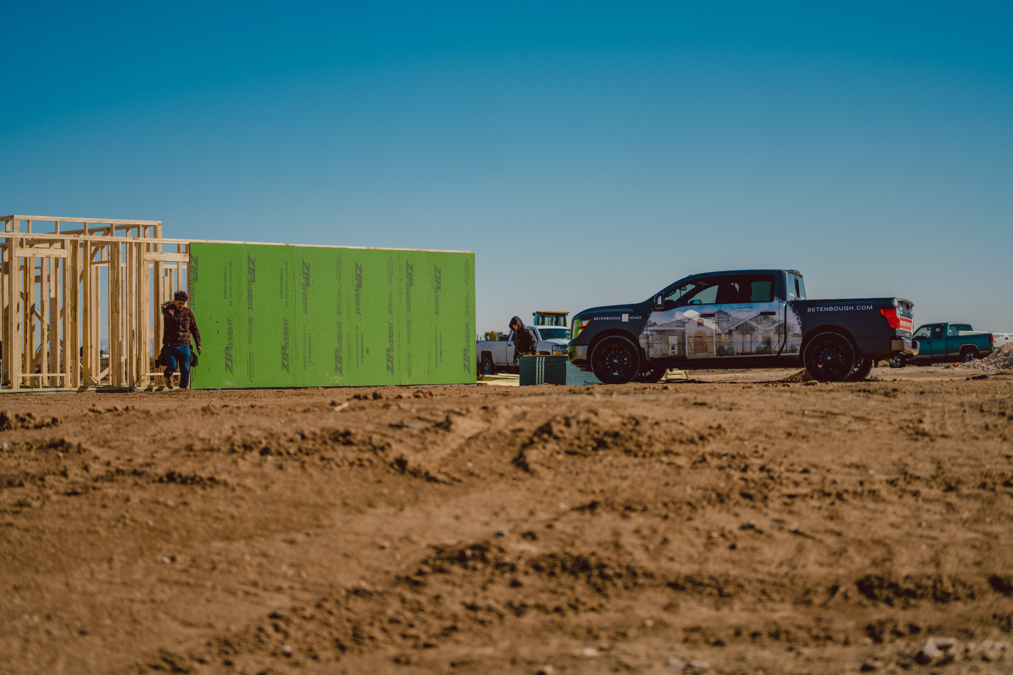 Photo of a Betenbough Homes truck at the site of a home being framed.