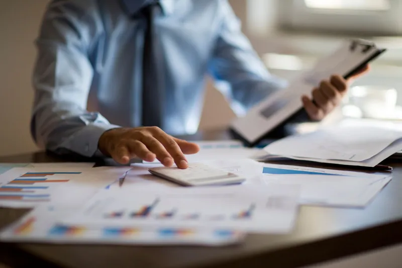 Photo of a man at a desk with a clipboard and a calculator representing calculating interest rates.