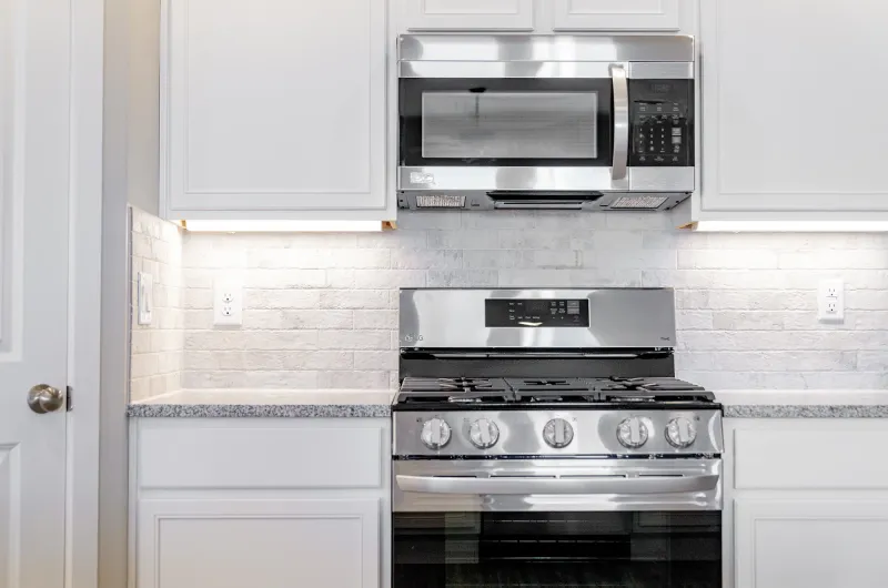 Photo of a gas range with a microwave installed above it in a Betenbough kitchen.