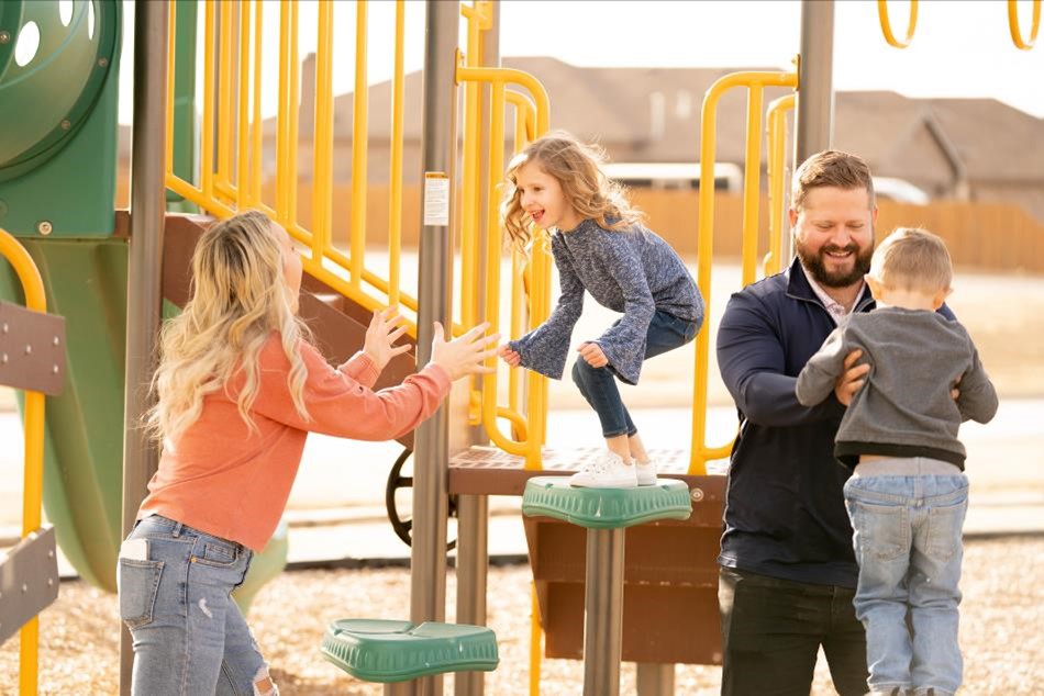 Photo of a family of four playing together in a community park.