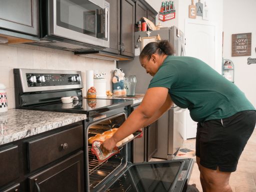 Photo of a woman pulling homemade hot rolls out of the oven in a Betenbough kitchen.