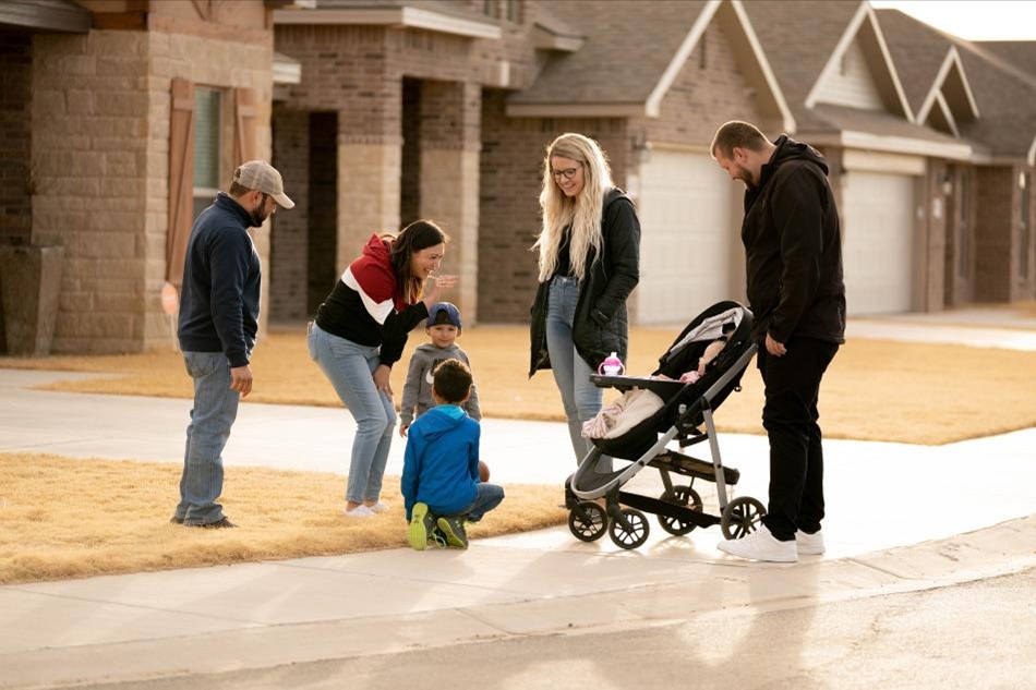 Photo of two families with children greeting each other as they walk in their Betenbough Homes community.