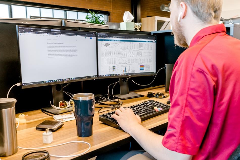 Photo of an employee working at a computer on a desk.