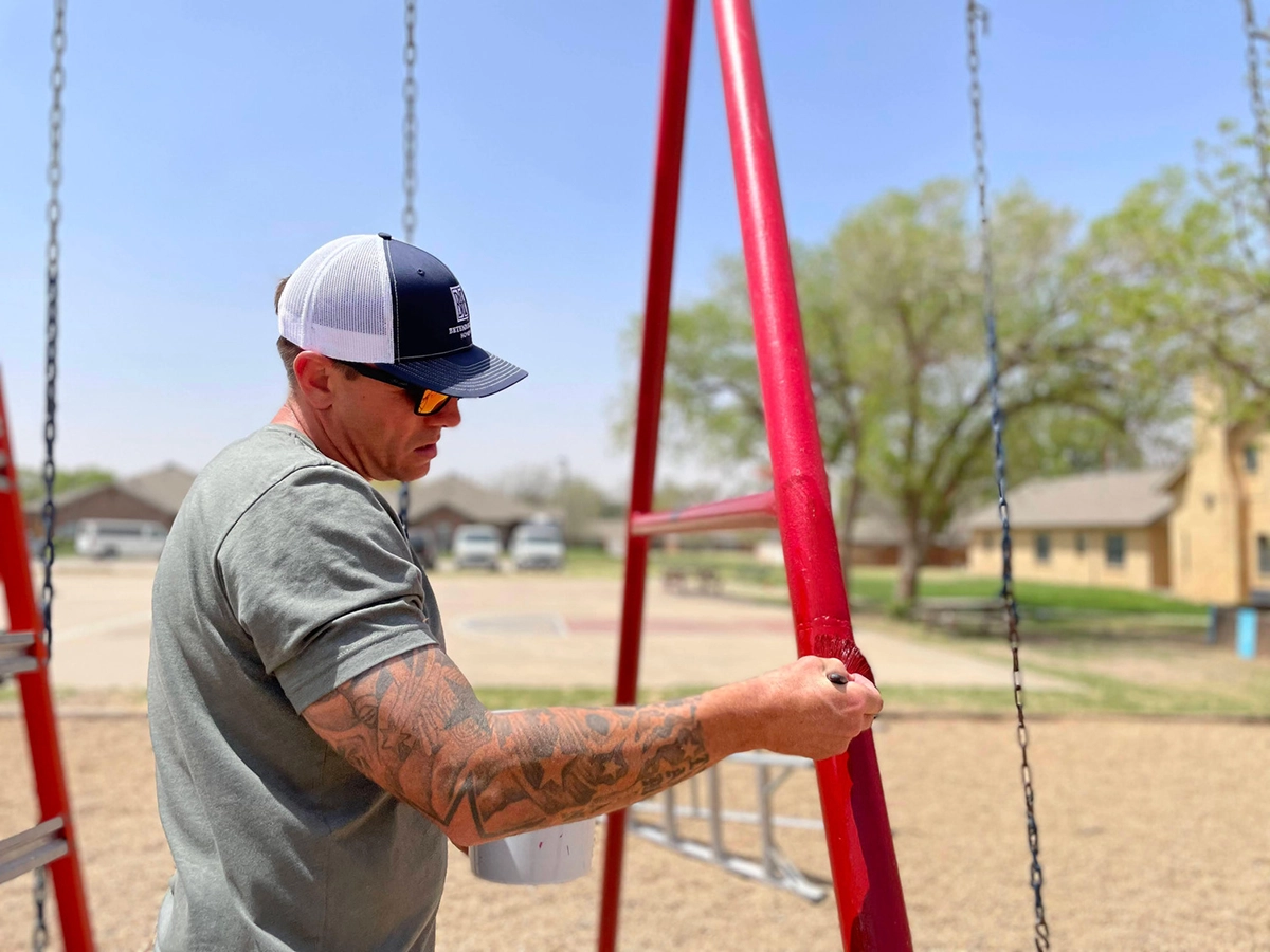 Betenbough employee painting a swing set