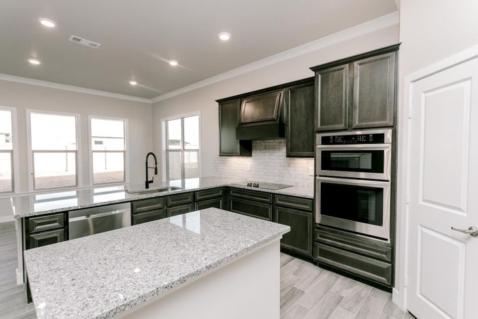 Photo of a Betenbough home kitchen with dark cabinets, granite countertops, and a tiled backsplash.