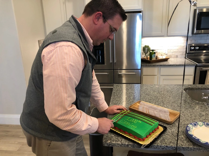 Ky Thomas cuts a cake with green icing that says