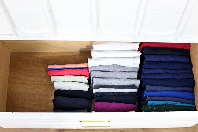 Photo of folded t-shirts arranged neatly in a drawer.