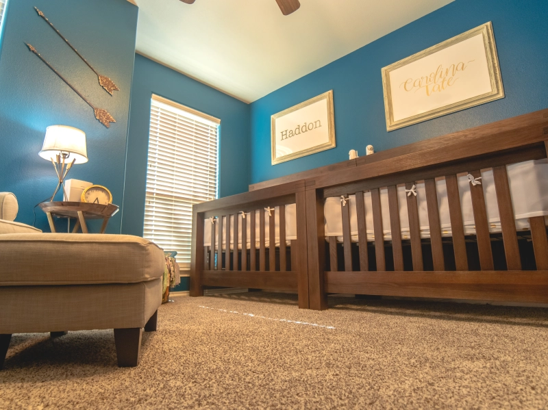 Photo of a twin's nursery with two cribs, furniture, and wall hangings.