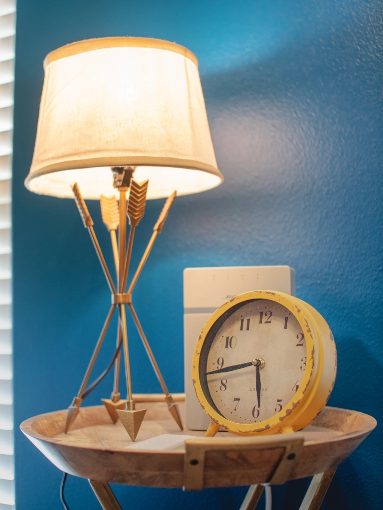 Photo of a side table in the nursery with a lamp and clock.