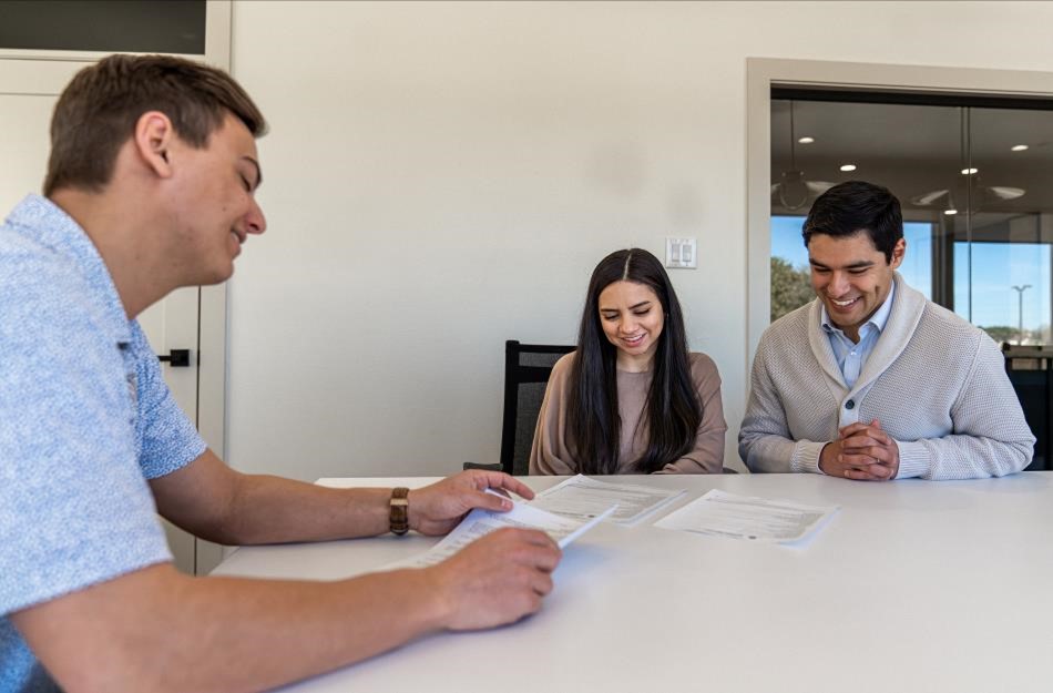 Photo of home buyers looking over paperwork with a Betenbough Homes employee.