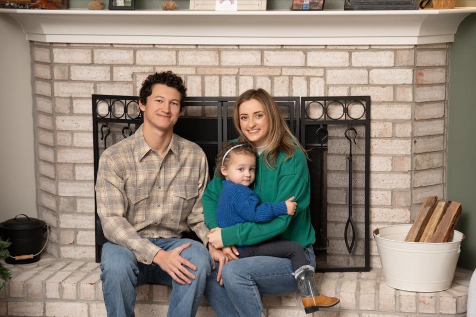 Photo of a family in their Betenbough home posing in front of the fireplace.