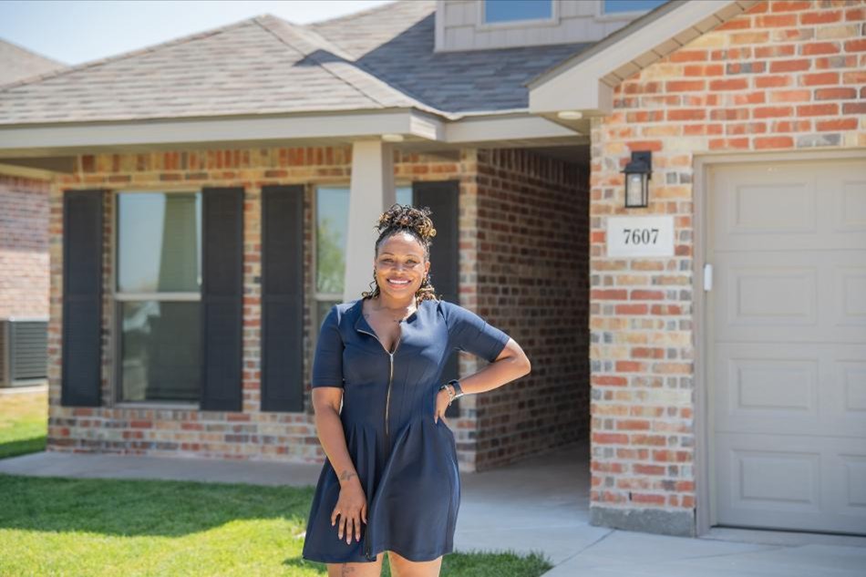 Photo of a first-time home buyer smiling with pride outside her new Betenbough home.