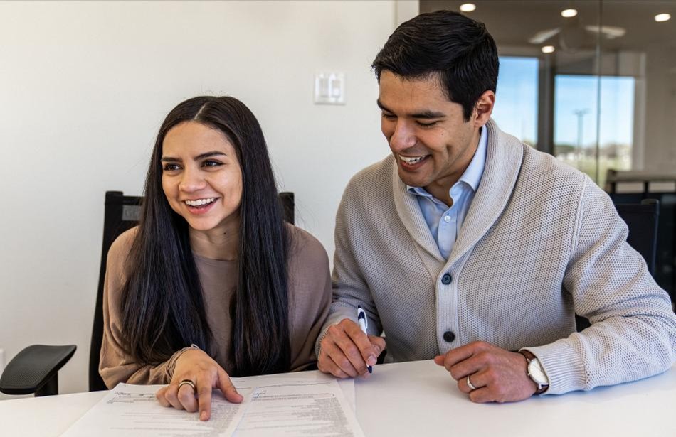 Photo of home buyers looking over paperwork on their new home, excited about the tax write-offs that homeownership will give them.