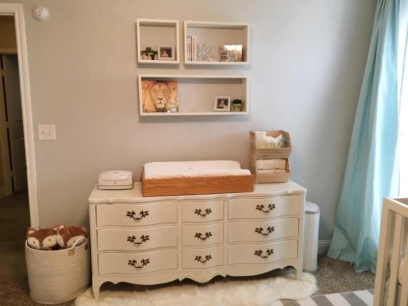 Photo of a vintage dresser being used as a changing table. Floating shelves are hung above.